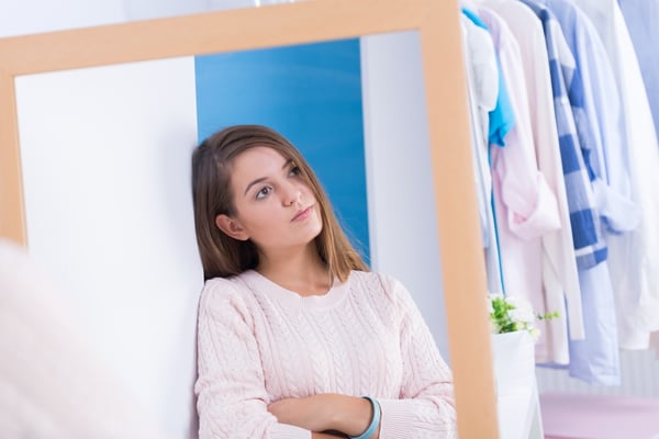  teen girl standing in front of mirror